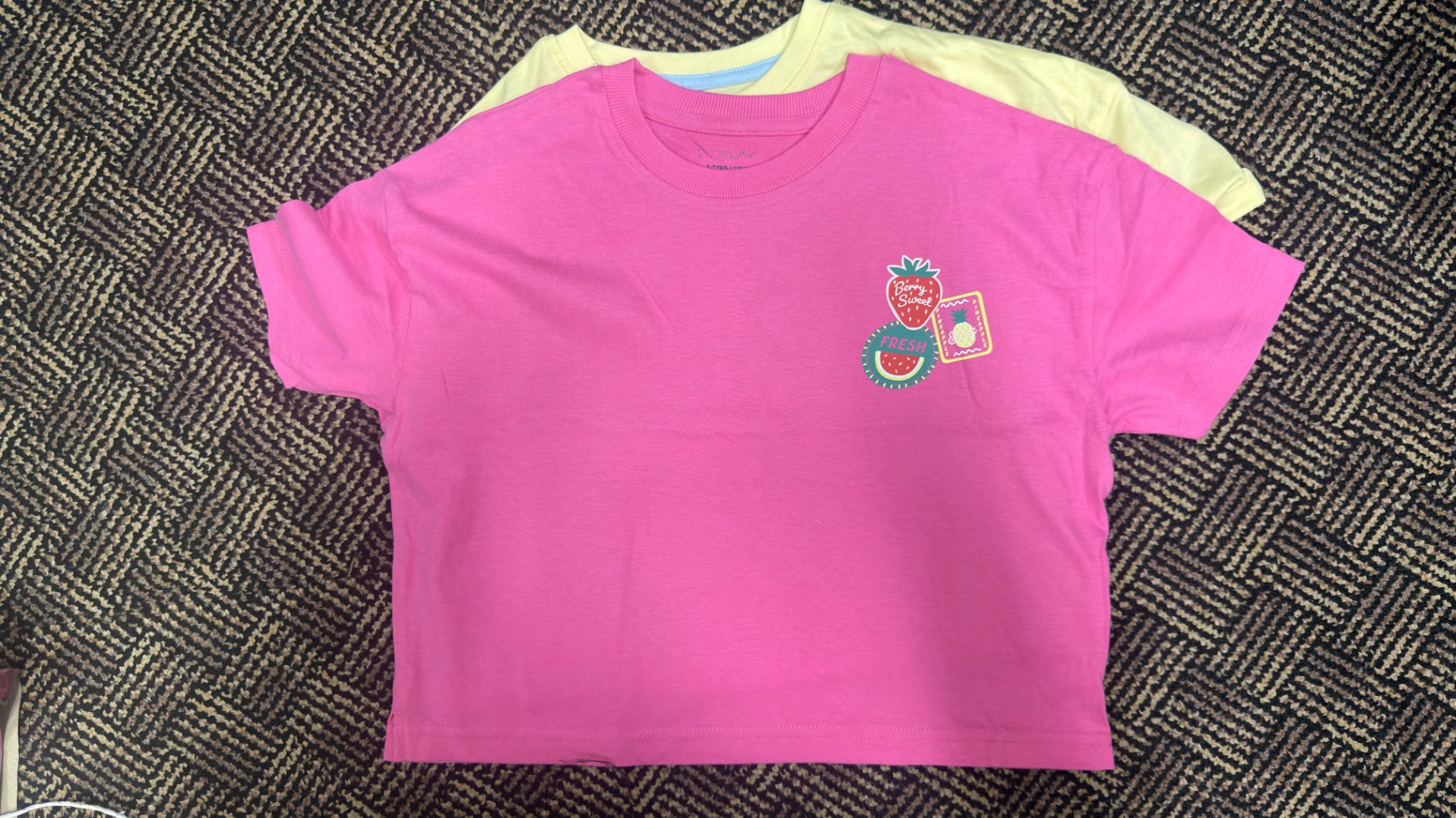 Historical third-party reference: pink crew-neck T-shirt with a small fruit print
